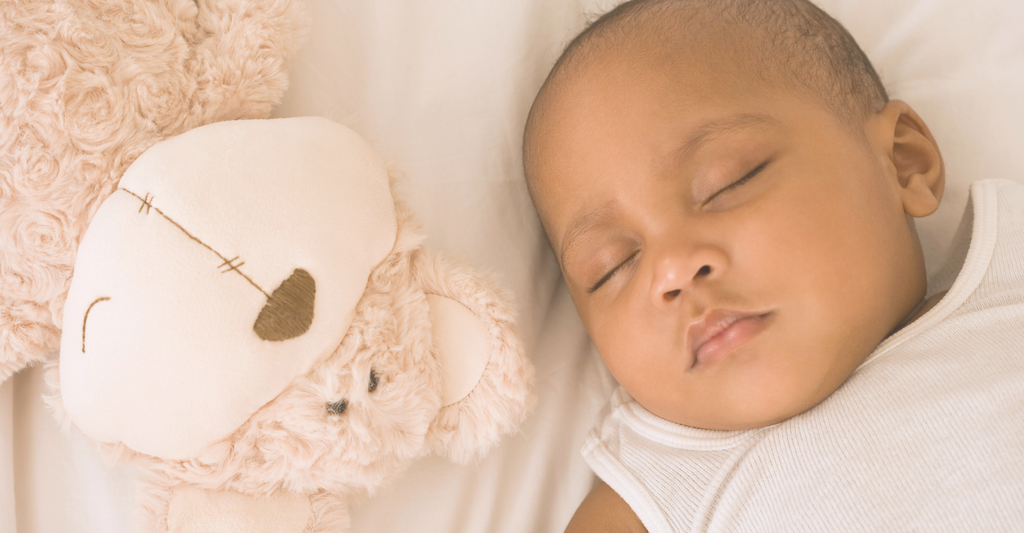 baby sleeping next to a stuffed animal